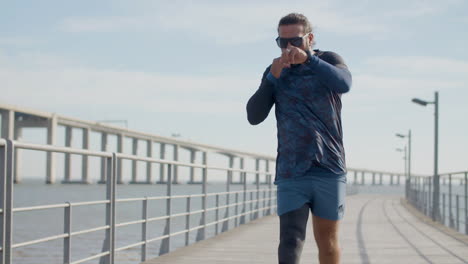 Front-View-Of-A-Focused-Sportsman-With-Prosthetic-Leg-Running-Outdoors-And-Punching-In-Air-In-The-Morning