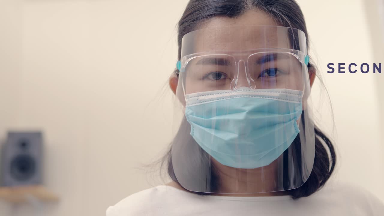Slow-motion close up of Asian woman in protective face mask and opens eyes looking straight at the camera with text Second wave COVID-19