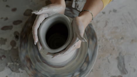 woman shaping pottery on a pottery wheel