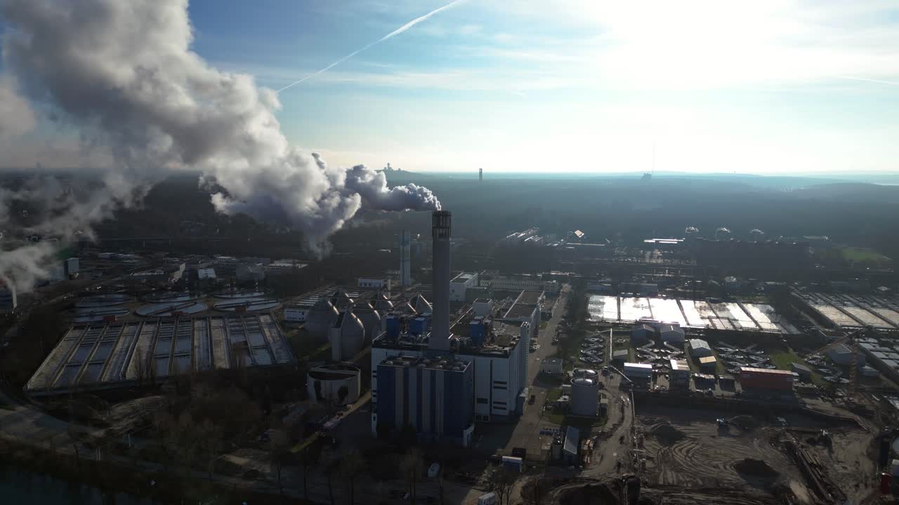 Waste to energy plant emitting smoke from its chimney, located near an urban area, environmental impact of waste. Fantastic aerial view flight drone top down Above view