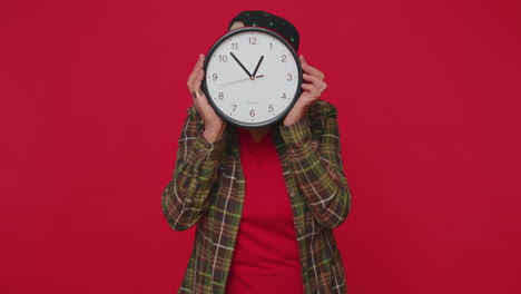 senior woman holding clock watch, hiding, checking time on clock running late to work being in delay