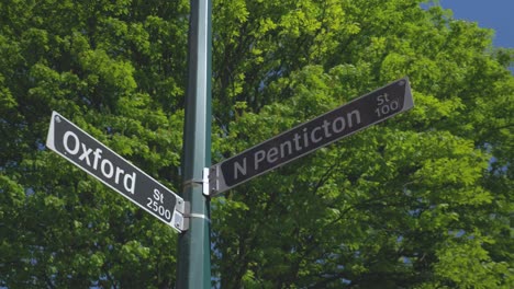 Sign-post-at-the-corner-of-Oxford-st-and-N-Penticton-Vancouver-BC-medium-wide-looking-up-angle-slow-orbit-left-stabilized