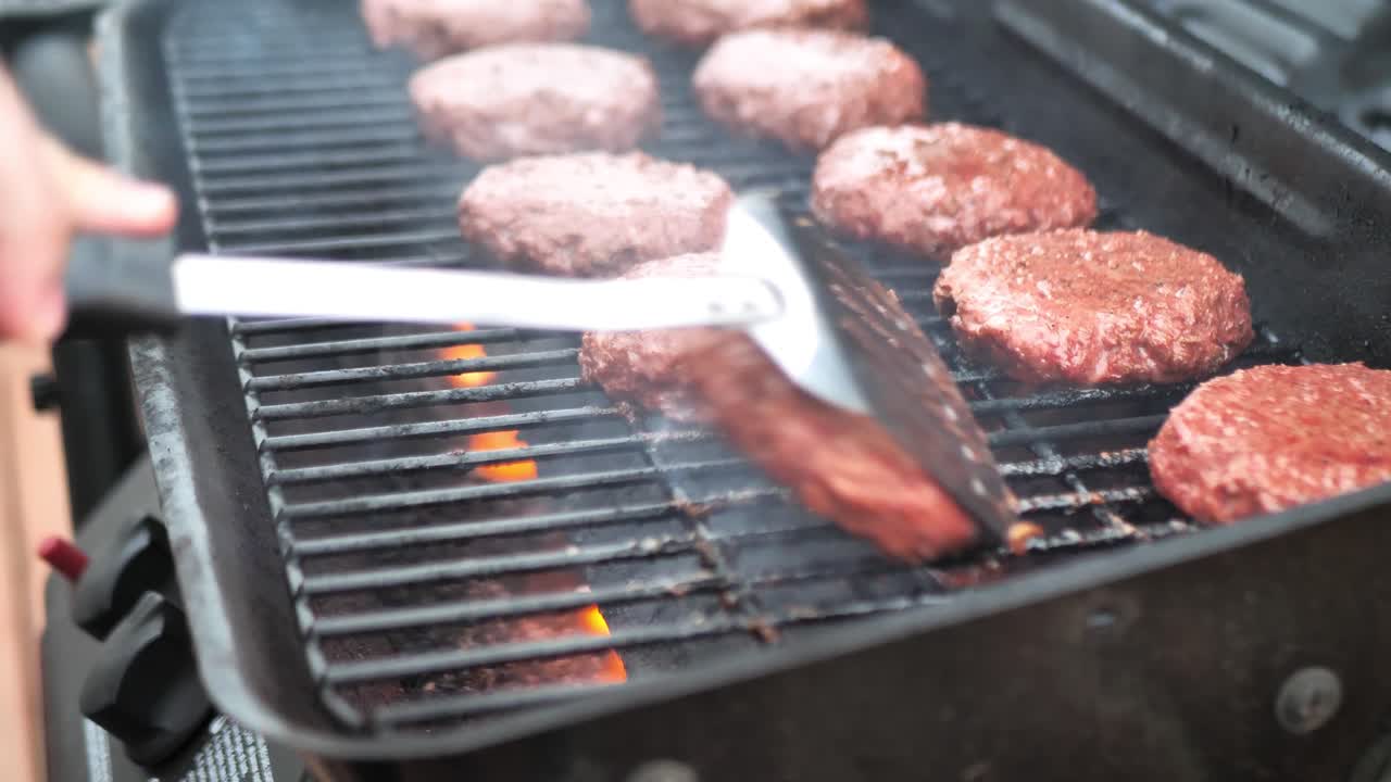 Coperchio che si apre sul grill e spatola che gira hamburger vegetali su un barbecue, inquadratura ampia in panning con fiamma al rallentatore 4K.