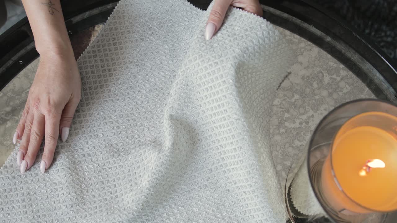 mujer trabajadora presentando telas en una mesa con una vela