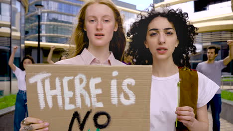 le donne che tengono non c'è pianeta b bordo e fiore margherita su una protesta