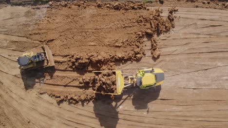 a bulldozer and a dump truck make short work of fresh earth being distributed into a construction site