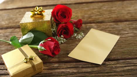 red roses, gift boxes and card on a wooden surface 4k