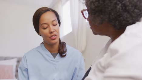 mixed race woman being visited at home by a nurse. social distancing and self isolation in quarantin