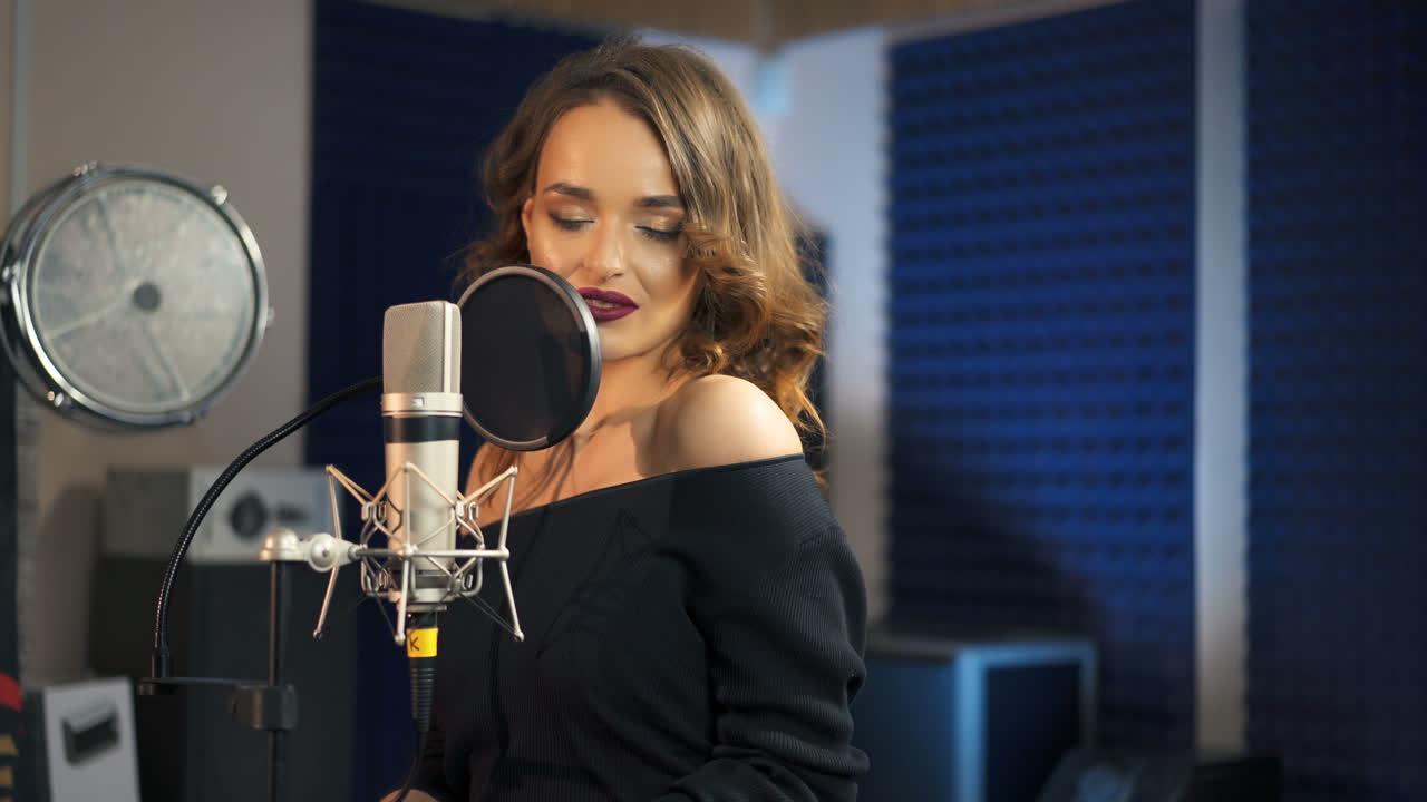 Bella donna che canta in un grande microfono. Studio di registrazione professionale