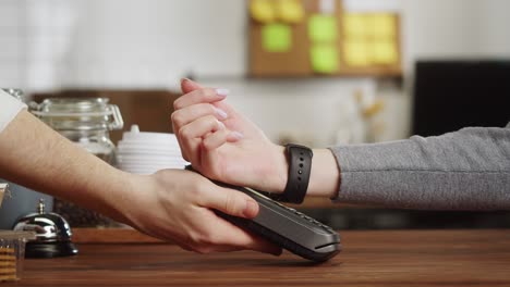 pagar con reloj inteligente en cafés. compras sin contacto, sin contacto en pubs. concepto de tecnología nfc, utilizando pago de pulsera de fitness a través de un primer plano de terminal.