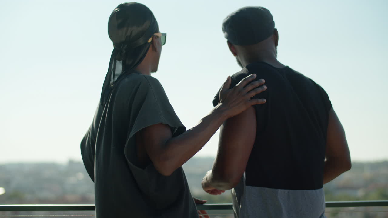 도시 경관을 바라보며 포옹하는 행복한 게이들의 중간 샷