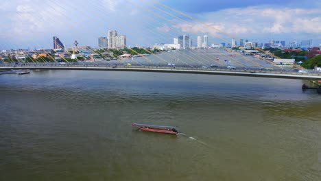 colorful longtail boat sailing on chao phraya river near rama viii bridge in bangkok, thailand