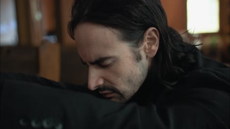 Young-man-in-black-suit-praying-in-church-pew-in-cinematic-slow-motion-with-folded-hands