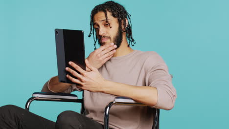 Person with disability doing digital art on drawing tablet, studio background