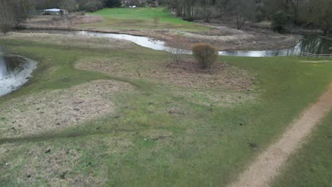 A-winding-river-in-southern-park,-norwich,-with-lush-greenery,-aerial-view