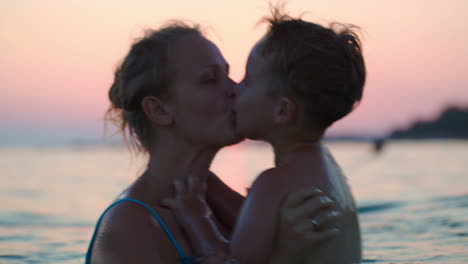 mother and son having fun in sea at sunset