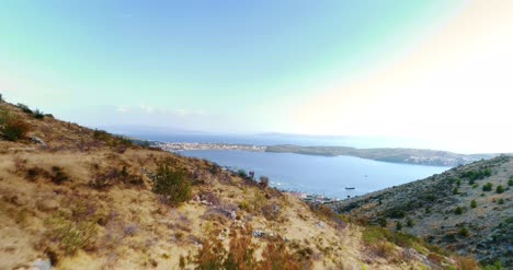 Vista-Aérea-Footage-Soaring-Over-Montaña-Range-And-Descending-To-Coastal-Village