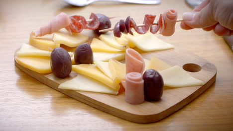 wooden board with cheeses, ham and olives