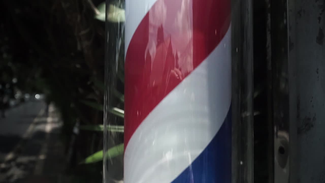 este es un cartel de poste de barbero que informa sobre el salón de peluquería