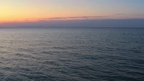 aerial flying above peaceful ocean sea at sunset, vast infinite horizon, sunset