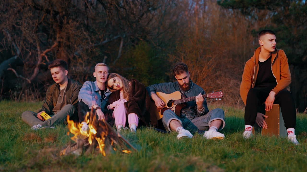 Young friends having fun near bonfire. Company of young friends having picnic near bonfire