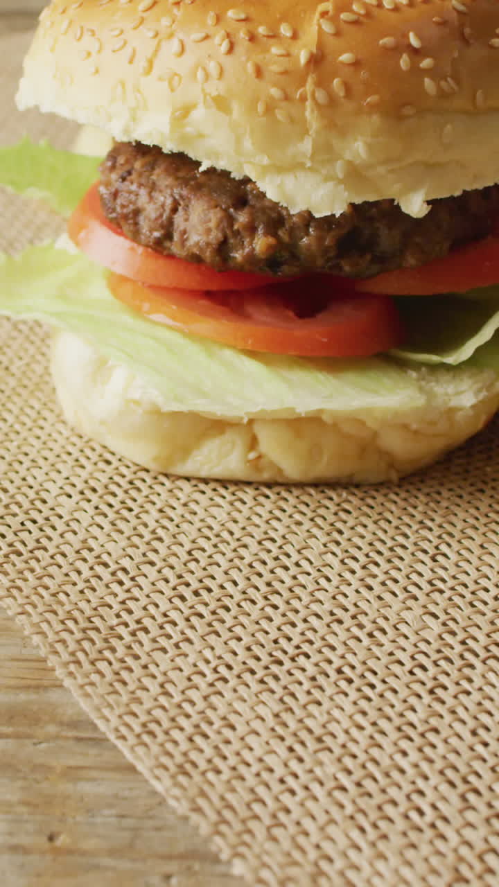 video de dos hamburguesas y papas fritas en tela de saco y mesa de madera