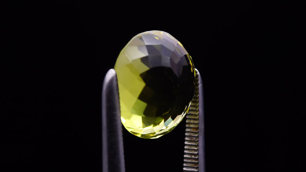 자연 황색 시트린은 회전 테이블에 있는 핀세저에 있습니다.