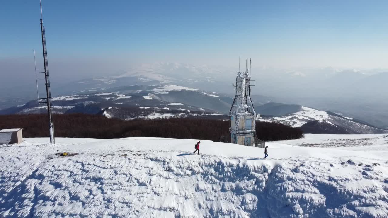 두 명의 기술자가 도시 마을의 전원 공급 장치를 제어하고 수리하는 눈과 얼음으로 덮인 송전탑 전기 철탑의 조감도