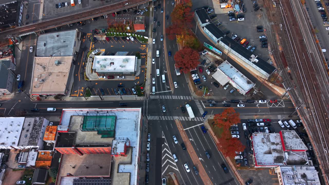 A high angle, aerial view of a busy intersection by Long Island Railroad elevated train tracks on Long Island. Taken on a cloudy day. the camera is stationary