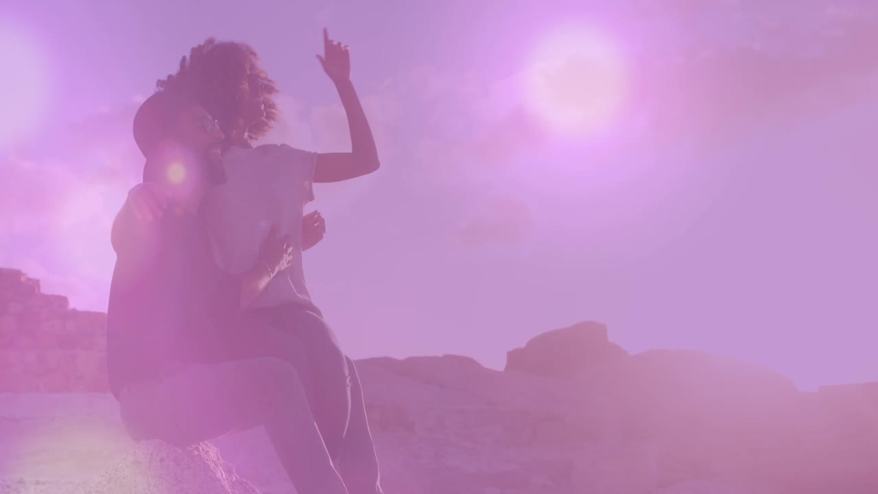 manchas de luz flotando contra una pareja afroamericana hablando entre sí en la playa