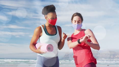 Animation-Von-Flecken-über-Glücklichen,-Vielfältigen-Freundinnen-Mit-Gesichtsmasken-Am-Strand