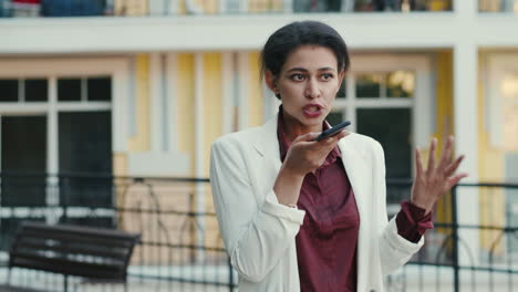 Angry-businesswoman-talking-mobile-phone-outdoors.-Focused-lady-discussing-phone