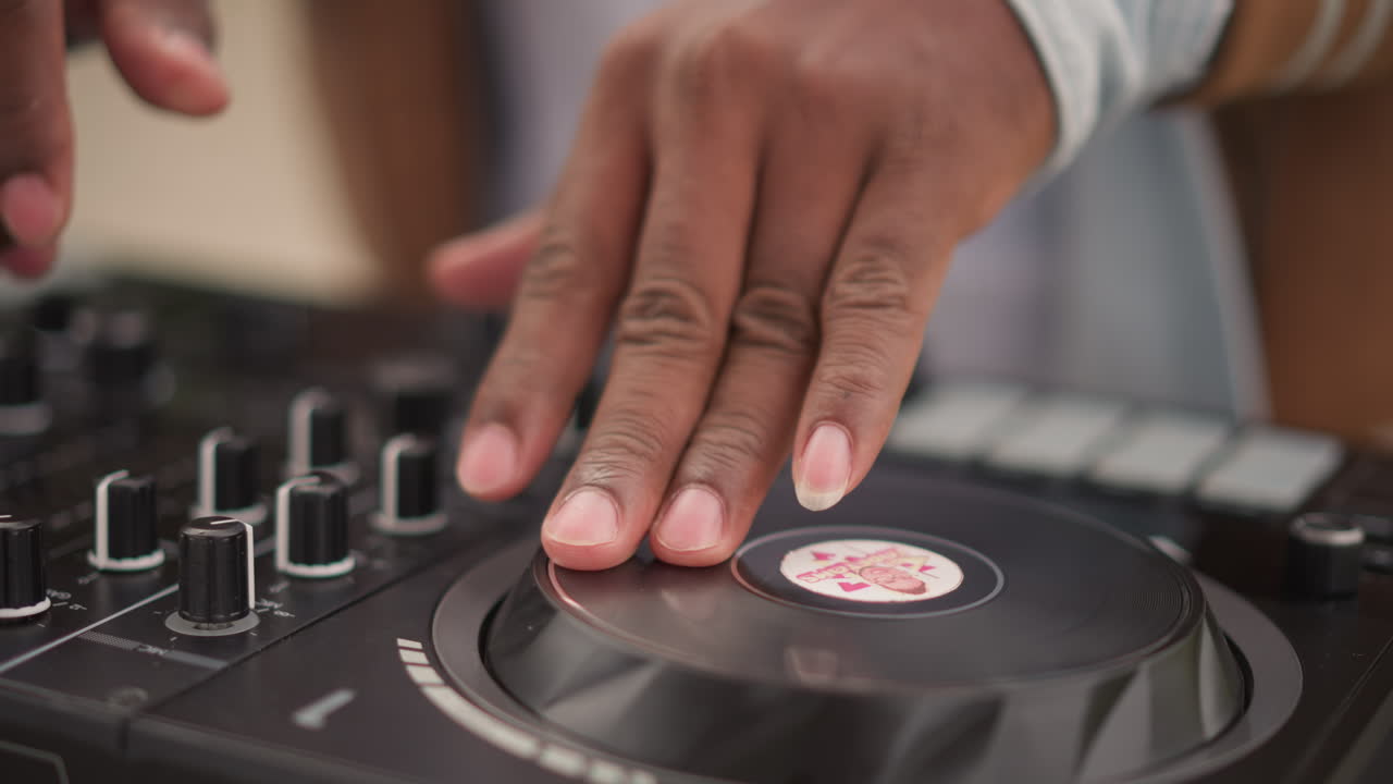 Primo piano delle mani di un DJ nero che regola le manopole sul controller, dita che lanciano beat con intenti, inquadrature che mostrano soundcheck per un radio edit, set live underground, loop di prova, editing in studio, canale di precisione.