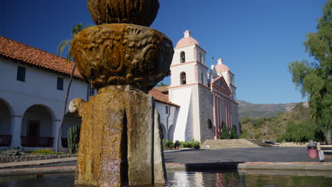 the historic building of the santa barbara california mission with fountain water reflecting the spanish catholic architecture slide right