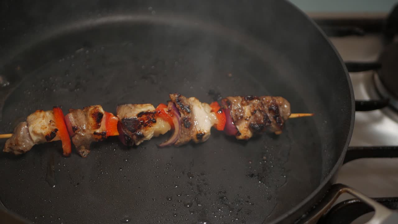 Spiedino di carne e verdure cotto in una padella nera nell'olio di arachidi.