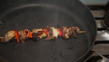 meat and vegetable skewer cooked on a black pan in peanut oil