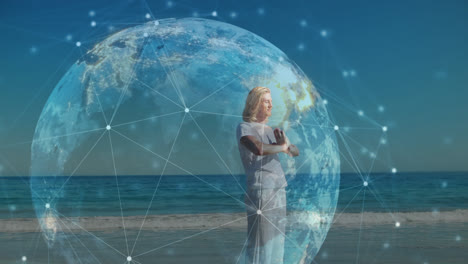 animation of network of connections and globe over practicing yoga on the beach