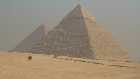 antiguas pirámides de egipto cerca de el cairo con camellos corriendo por la arena caliente del desierto