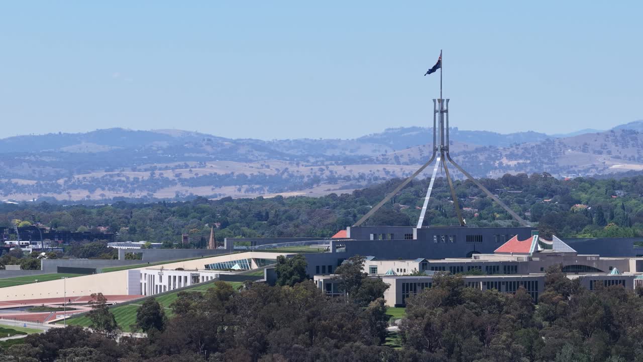 Plano general estático de la Casa del Parlamento Australiano con la bandera nacional ondeando en lo alto.