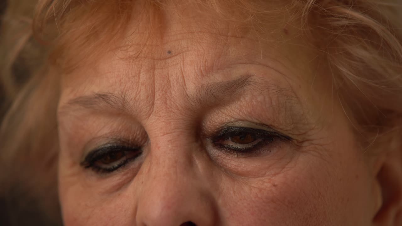 fotografía macro de la cara de una mujer de edad avanzada. retrato recortado de una mujer anciana con arrugas alrededor de los ojos marrones. primer plano de los ojos de una mujer madura seria