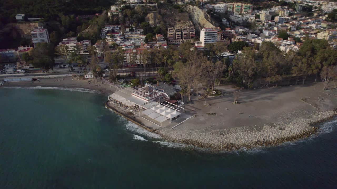 Drone shot of a caf&eacute; on the beach beside a city