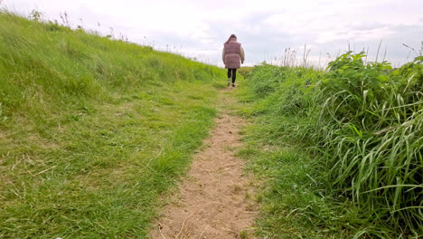 sandy country path surrounded by grass, sand dunes and a old wooden fence