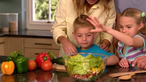 Smiling-family-preparing-salad-in-kitchen