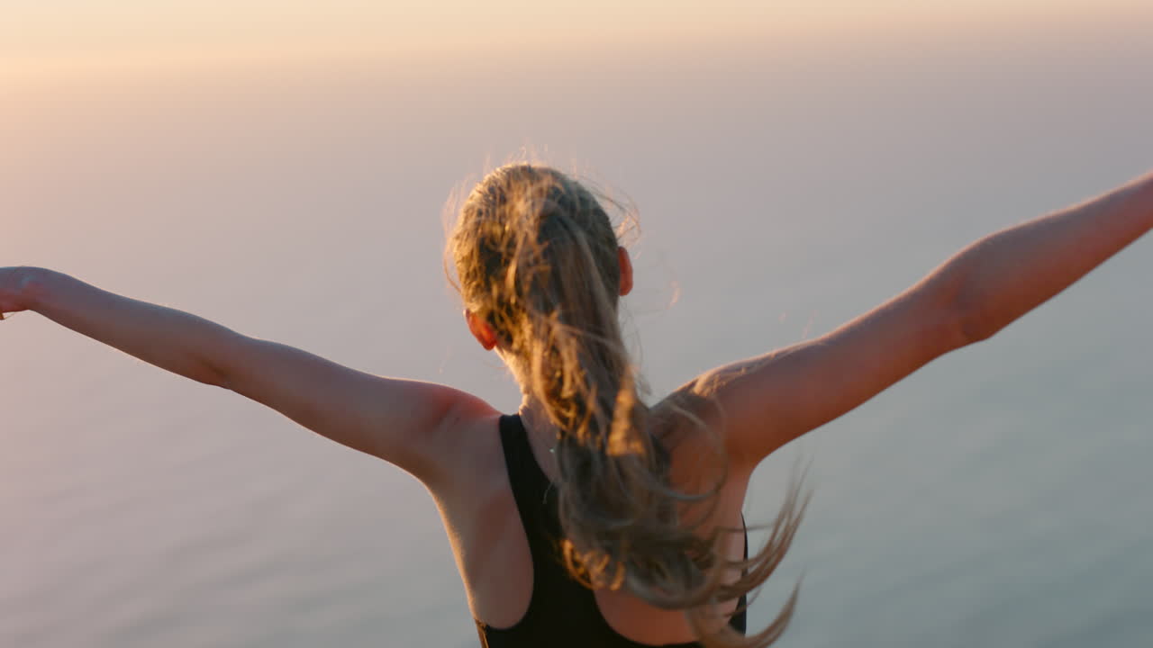 donna indipendente con le braccia alzate in cima alla montagna che celebra il successo ragazza sul bordo di una scogliera che guarda la splendida vista al tramonto che gode dell'avventura di viaggio
