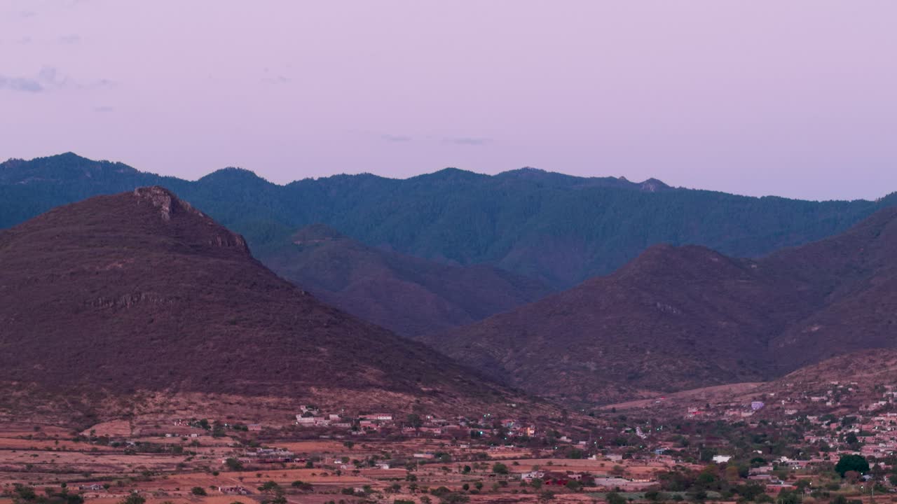 Scena aerea crepuscolare di montagne e una piccola comunità nella valle, Oaxaca