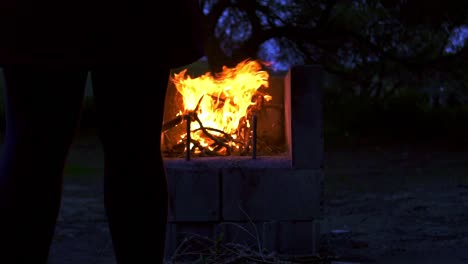 Slow-motion-dolly-shot-of-a-silhouette-standing-in-front-of-a-campfire