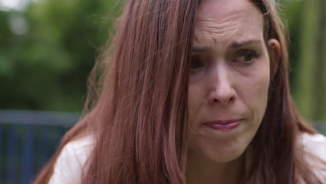 Close-Up-Of-Depressed-Woman-Outdoors-With-Financial-Worries-About-Cost-Of-Living-Crisis-Debt-And-Paying-Bills-Sitting-On-Bench