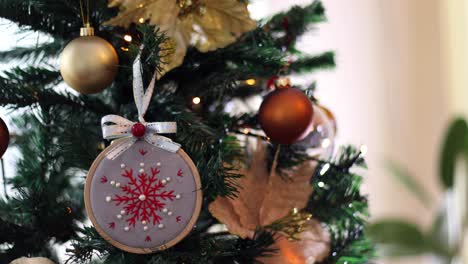 las manos de la niña poniendo ornamentación bordada en el árbol de navidad