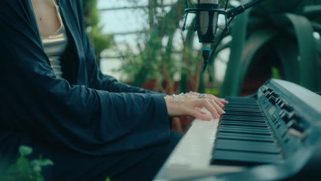 pearl-adorned hands of female musician playing keyboard in indoor garden
