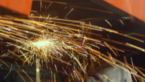 industry worker files metal parts with a circular saw, generating spectacular sparks
